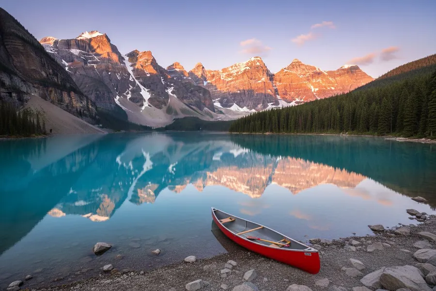Landscape Photo example: Turquoise alpine lake surrounded by pine forest and snowy peaks, a red canoe on the shore,...